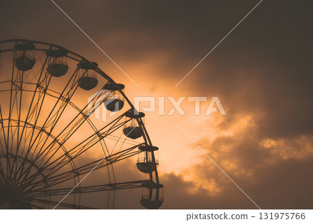 摩天輪的輪廓漂浮在夕陽的天空中。懷舊浪漫的場景 131975766
