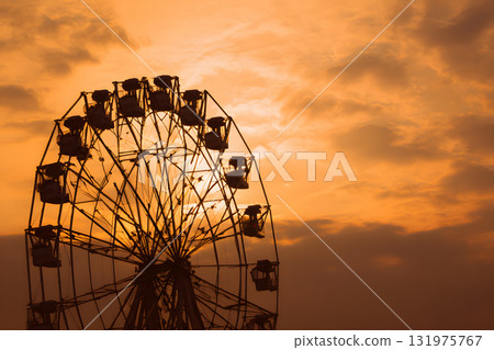 摩天輪的輪廓漂浮在夕陽的天空中。懷舊浪漫的場景 131975767