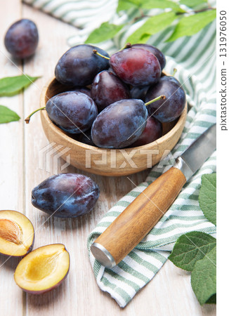 Fresh plums in wooden bowl with knife 131976050