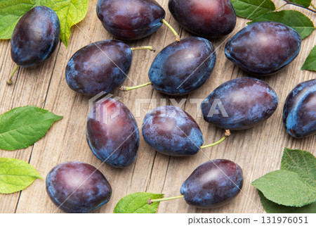 Ripe purple plums fallen on wooden table 131976051