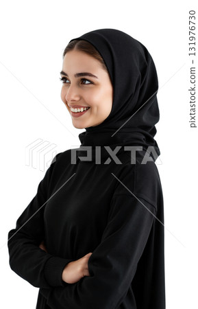 Woman Hijab Smiling. A young woman wearing a black hijab and abaya smiles warmly while looking off to her right 131976730