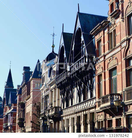 Historic European townhouses: one half-timbered style, the other red brick Neo-Renaissance, featuring intricate gables against a clear blue sky in Antwerp, Belgium 131978242