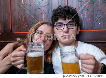A middle-aged woman celebrates Mother's Day with her son by drinking a beer together. Looking into the camera, the lifestyle of celebrating with beer. A middle-aged woman celebrates Mother's Day with her son by drinking a beer together. Looking into the camera, the lifestyle of celebrating with beer. 131979098