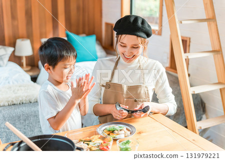 Family enjoying cooking together, preparing meals and serving curry at a cottage (family trip/glamping) Family enjoying cooking together, preparing meals and serving curry at a cottage (family trip/glamping) 131979221