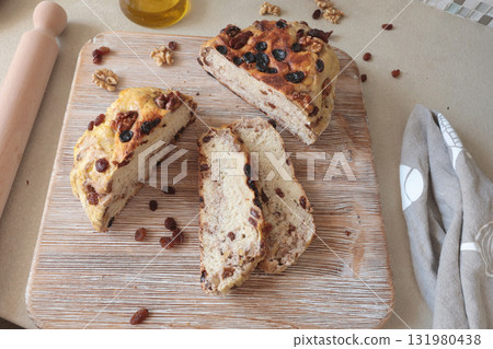 Homemade bread on wooden board with walnuts and raisins. Food and organic products. Hobbies and cooking in kitchen. 131980438