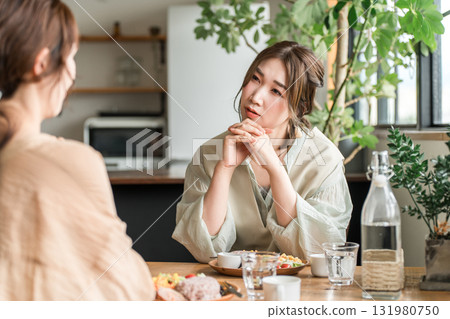 Young Asian woman discussing her worries with a friend in a cafe 131980750