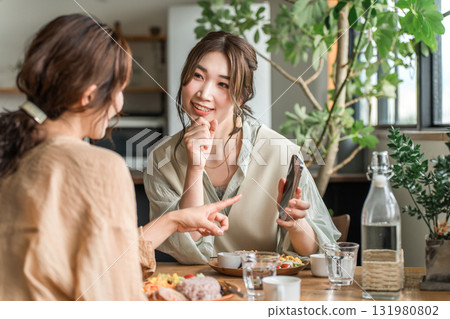 Cafe, coffee shop, woman talking while looking at smartphone at dining table Cafe, coffee shop, woman talking while looking at smartphone at dining table 131980802