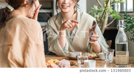 Cafe, coffee shop, woman talking while looking at smartphone at dining table 131980803