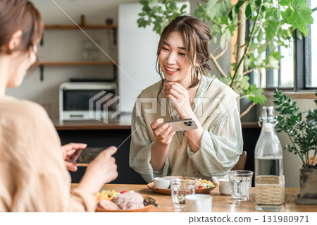 A woman taking photos of food on her smartphone while visiting cafes 131980971