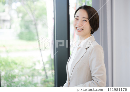 A woman in a suit in the office, looking at the camera with a smile, as if she is a consultant or recruiter. 131981176