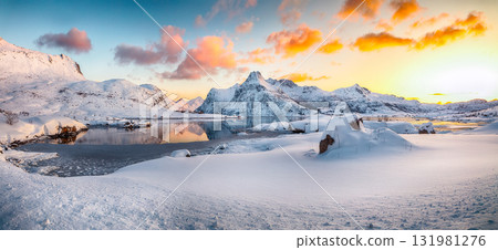 Amazing Flakstadpollen and Boosen fjords with cracks on ice during sunrise with Hustinden mountain on background. Amazing Flakstadpollen and Boosen fjords with cracks on ice during sunrise with Hustinden mountain on background. 131981276