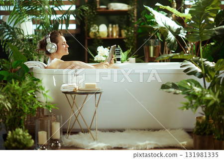 Serene Woman Enjoying Bath with Tablet & Headphones 131981335