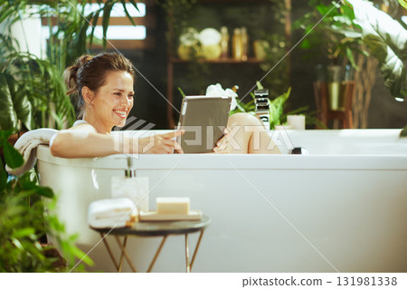 Woman\'s Joyful Tablet Time in a Green Bathtub Oasis 131981338