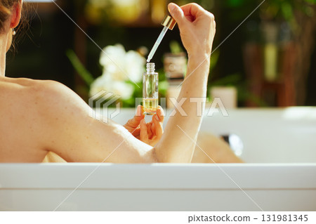 Woman Dispensing Bath Oil with Dropper Woman Dispensing Bath Oil with Dropper 131981345