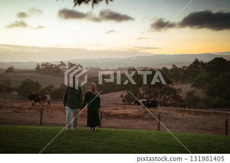 Couple at sunset holding hands in a peaceful rural setting with cows 131981405