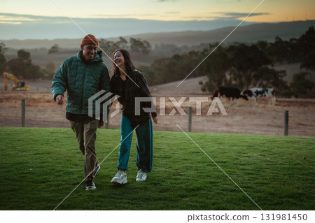 Joyful Couple Walking Together in a Scenic Outdoor Setting at Sunset 131981450