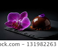 Gourmet chocolate mousse dessert with a mirror glaze and a fresh orchid flower on a slate plate 131982263