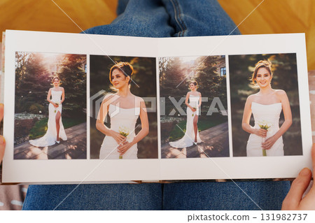 Female hands flipping through a photo book with wedding photos 131982737