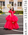 A cute little girl in an elegant lush pink dress is playing on the sports ground 131982738