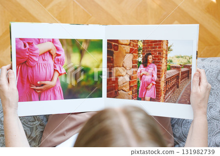 woman is holding and flipping through a photo book with a pregnancy photo shoot 131982739