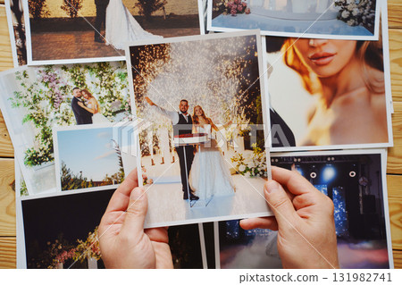 Men's hands put on the table and show wedding photos. 131982741