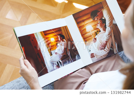 woman is holding and flipping through a photo book with a pregnancy photo shoot 131982744