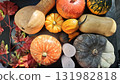 Various colorful pumpkins and gourds arranged with red autumn leaves on a dark background 131982818