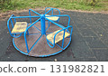 Old blue and yellow playground carousel on rubber tiles in an empty park 131982821