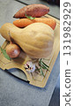 Fresh vegetables arranged on a wooden cutting board including butternut squash, sweet potato, carrot, onion, and garlic. Concept of healthy cooking ingredients and autumn seasonal food 131982929