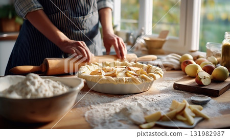 Person preparing homemade apple pie on a floured wooden table in a cozy kitchen Person preparing homemade apple pie on a floured wooden table in a cozy kitchen 131982987