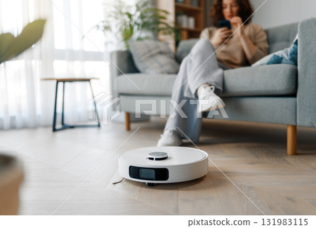 White robotic vacuum cleaner on wooden floor White robotic vacuum cleaner on wooden floor 131983115