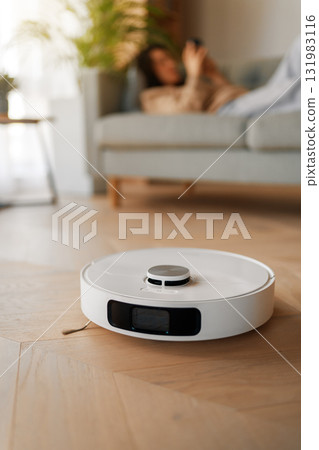 White robotic vacuum cleaner on wooden floor 131983116