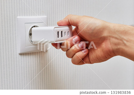 male hand insert a plug of the phone charger into socket at home 131983836