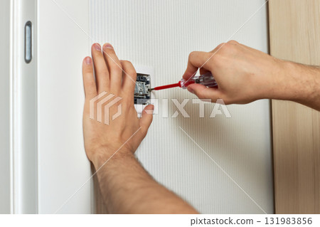 electrician working on light switch using screwdriver inside, close-up electrician working on light switch using screwdriver inside, close-up 131983856