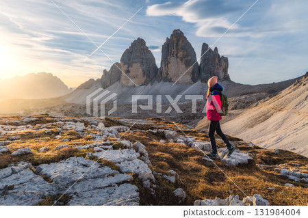Girl with backpack on the mountain peak and high rocks at sunset 131984004