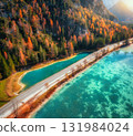 Aerial view of scenic road running along turquoise alpine lake 131984024