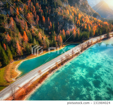 Aerial view of scenic road running along turquoise alpine lake 131984024
