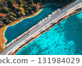 Aerial view of scenic road running along turquoise alpine lake 131984029