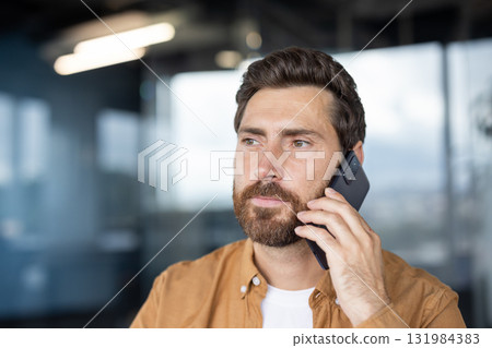 Professional man having a serious phone call, listening intently to the conversation and communicating through his mobile phone in a modern office environment 131984383
