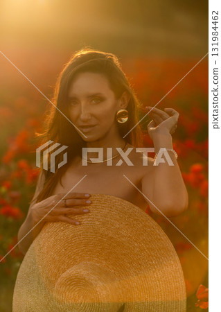 Woman in a field of red flowers holding a hat. Woman in a field of red flowers holding a hat. 131984462