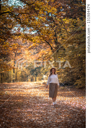 Woman Autumn Forest Path: Fall foliage scenic stroll, sunlight dappled leaves, peaceful nature scene. 131984474