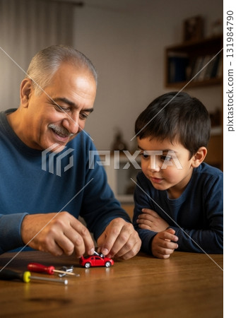 A loving grandfather teaching his curious grandson how to fix a toy car at home. Intergenerational family bonding and learning a new skill together A loving grandfather teaching his curious grandson how to fix a toy car at home. Intergenerational family bonding and learning a new skill together 131984790