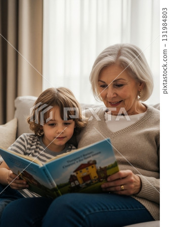 A grandmother reads a storybook to her young grandson on the couch. Senior woman and child sharing quality time together at home. Intergenerational family bonding and learning concept 131984803