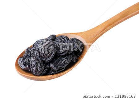 Black raisins in a wooden spoon close-up on a white. Isolated Black raisins in a wooden spoon close-up on a white. Isolated 131985162