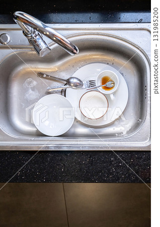 Dirty dishes in kitchen sink. Unwashed plates, bowls and cutlery Dirty dishes in kitchen sink. Unwashed plates, bowls and cutlery 131985200