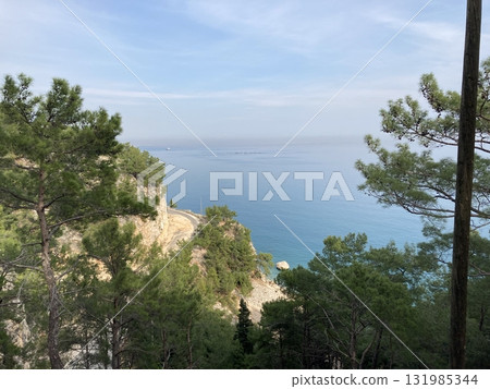 Abandoned scenic old road along the sea and cliffs, view from above from the cliff through the trees Abandoned scenic old road along the sea and cliffs, view from above from the cliff through the trees 131985344