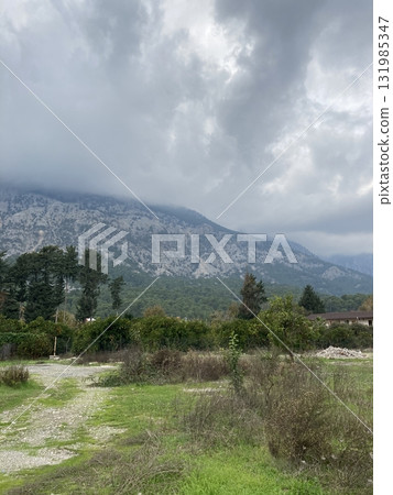 Low fluffy clouds hang over the high mountains, cover their peaks 131985347