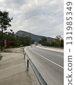The highway runs along the mountains, cars move along it 131985349