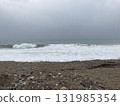 The turbulent sea storms the shore of sand mixed with pebbles 131985354