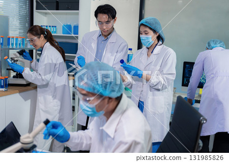 Team of biochemical research scientists working with a microscope for vaccine development Team of biochemical research scientists working with a microscope for vaccine development 131985826